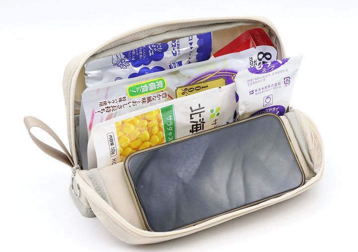 ベージュのポーチのメインスペースにレトルト食品などと一緒にスマートフォンが立てかけられている