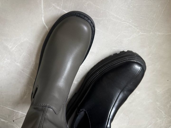グレーとブラックのブーツを並べて色味を比較している足元