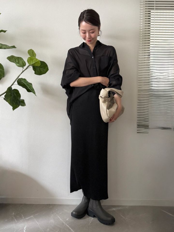 黒のシャツとロングスカートのワントーンコーデを着こなす女性