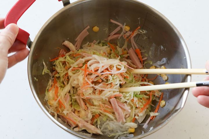 糸こんにゃくと野菜を調味料で和える様子