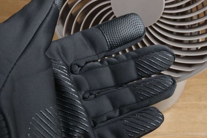 黒い防寒手袋を着用した手のひらをサーキュレーターの前にかざしている様子
