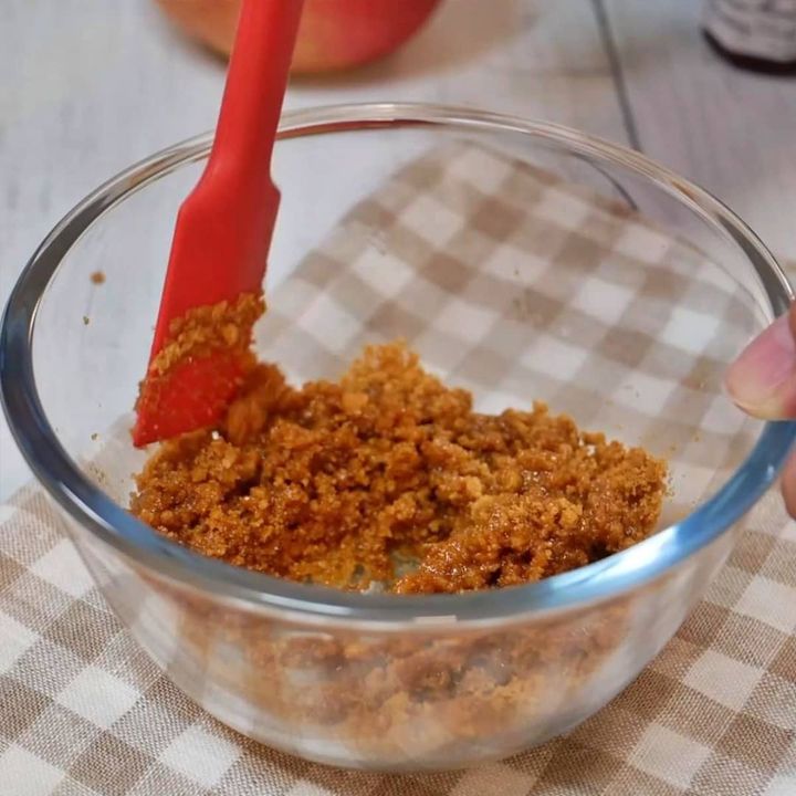 砕いたビスケットに溶かしバターを混ぜる様子