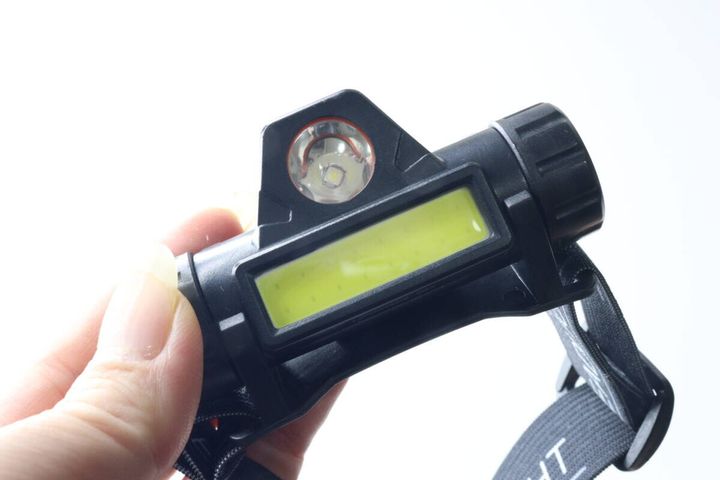 広角とスポットのランプが並ぶヘッドライト本体を指先で支えている様子
