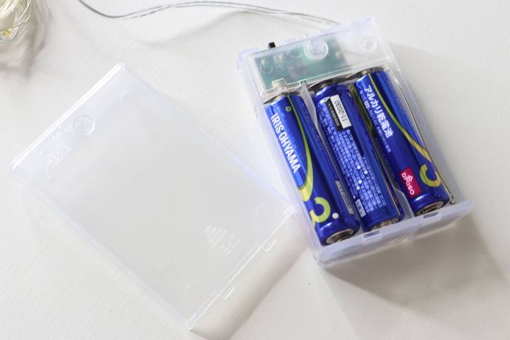 ストリングライトの電池ボックスに単3形乾電池3本を入れている様子。