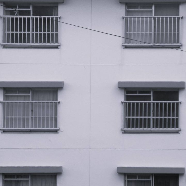 同じ形の窓とベランダが規則正しく並ぶ、集合住宅の外観。