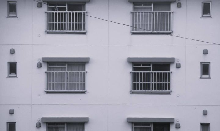 同じ形の窓とベランダが規則正しく並ぶ、集合住宅の外観。