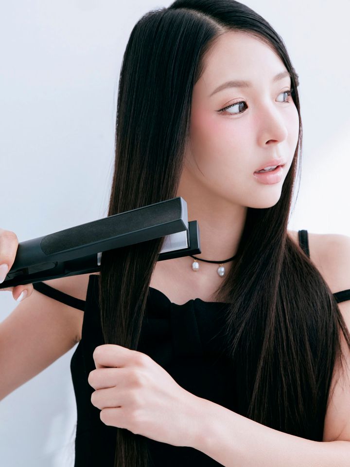 ストレートアイロンで髪の根元から毛先へ滑らせてスタイリングするミチ