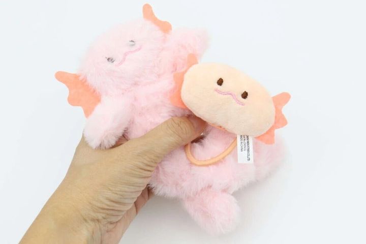 手で持たれているウーパールーパーの形をしたシュシュとヘアゴム