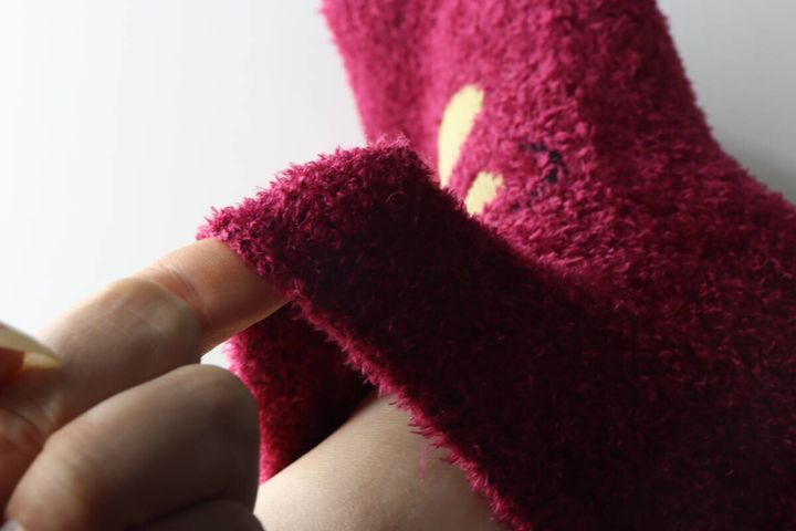 指でルームソックスの履き口を引っ張り伸縮性と生地の厚みを見せている様子