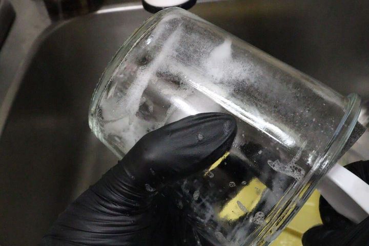絶妙な柄の長さのスポンジを使ってガラスの容器を洗っている様子