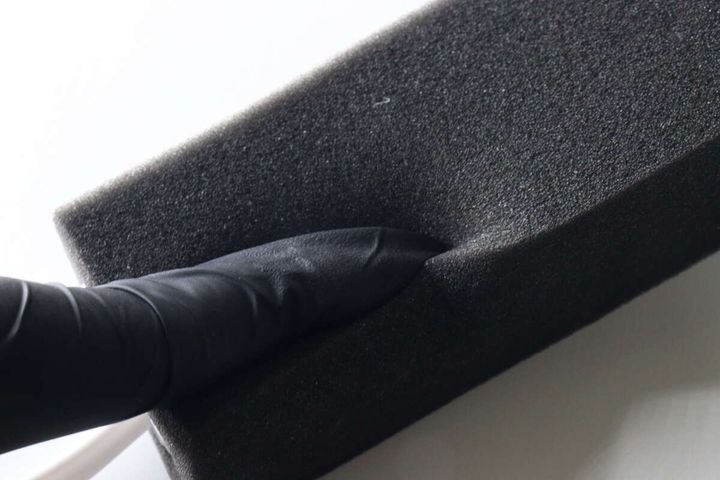 黒い手袋をした指でやわらかなスポンジの素材感を確認している様子