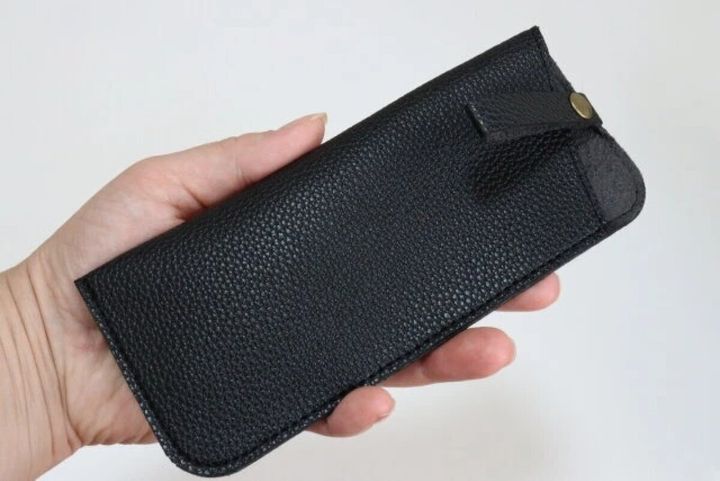 シボ感のある黒いソフトメガネケースを手に持っている様子