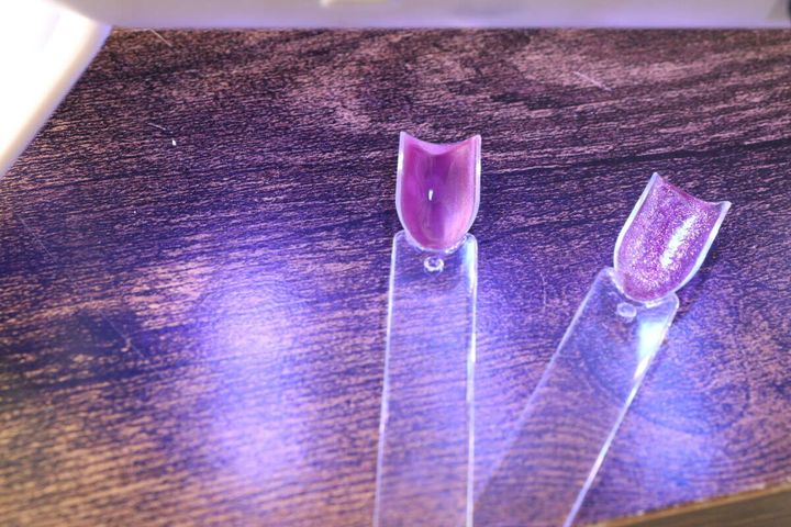 ライトの下でジェルネイルを硬化させているスティックの比較