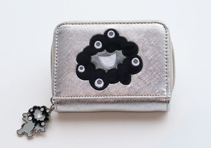 シルバーのミニ財布の正面アップ。黒いミャクミャクの刺繍と、ファスナーの引き手についたミャクミャクのチャームが見える
