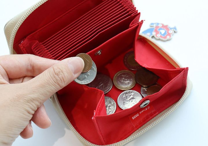 ミニ財布のボックス型小銭入れに硬貨が複数入っており、指で硬貨をつまんでいる様子