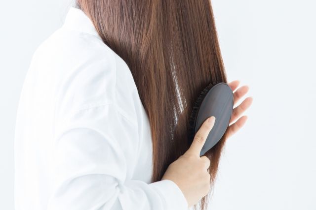 ブラシで髪の毛をとかすロングヘアの女性