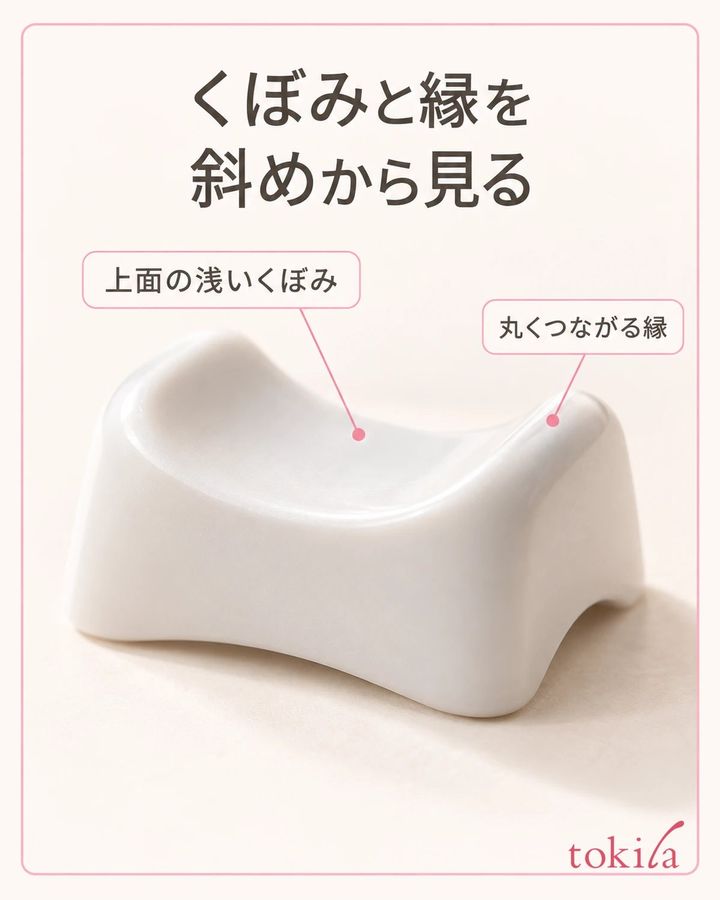 白い指置き台の浅いくぼみと丸い縁に横から光が当たる接写