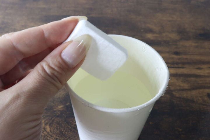 水を入れた紙コップに圧縮タオルを浸そうとしている瞬間
