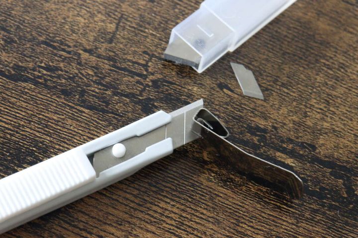 上部の金属製刃折器を使ってカッターの刃を折っている様子