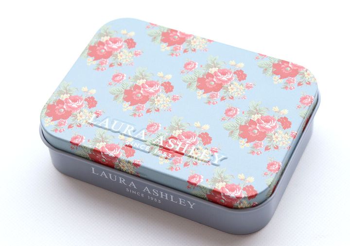 華やかなローズ柄が描かれ立体的なロゴが入ったブルーの缶ケース