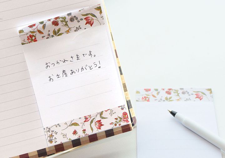 手帳に貼り付けられた小花柄のメモ付箋と手書きのメッセージ