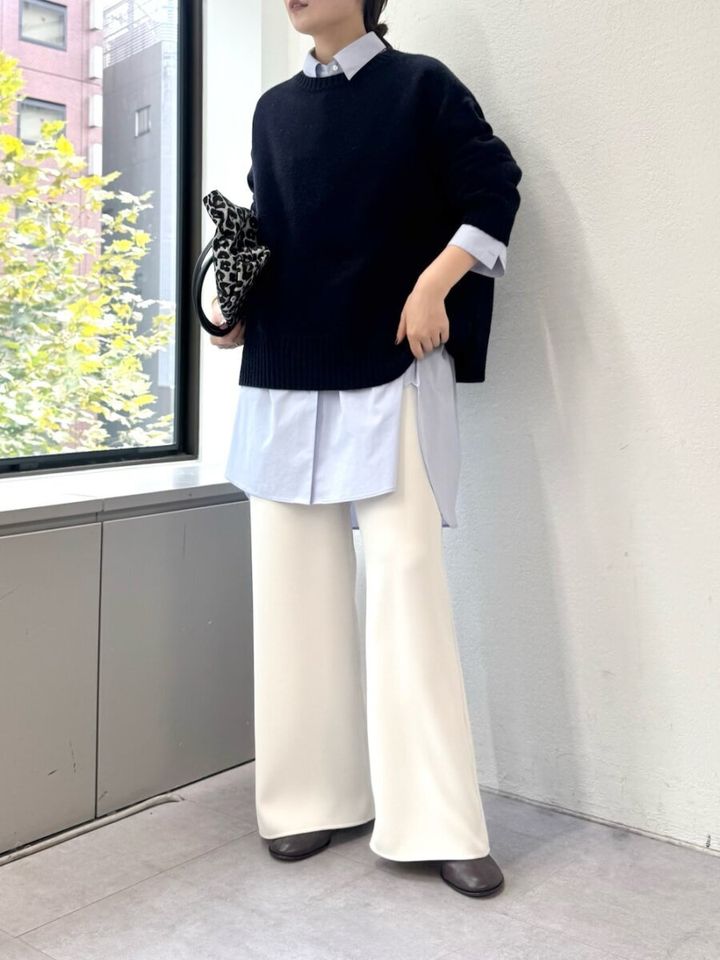 ブルーのシャツワンピースに黒ニットと白ワイドパンツを合わせる女性