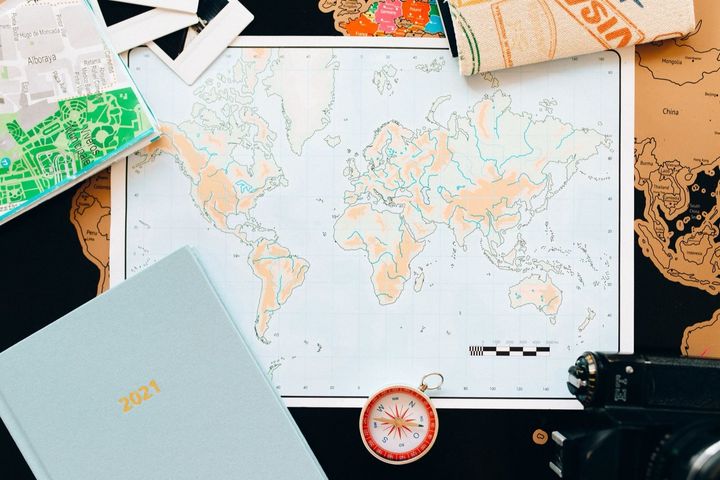 机の上に広げた世界地図です。方位磁針や手帳、ほかの地図も一緒に置かれています。