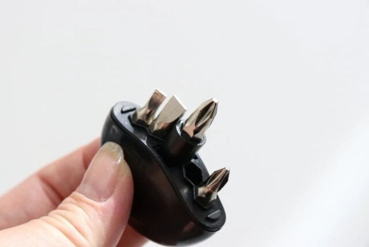 右手が黒いキーホルダー型ドライバーを持ちビット部分を見せている