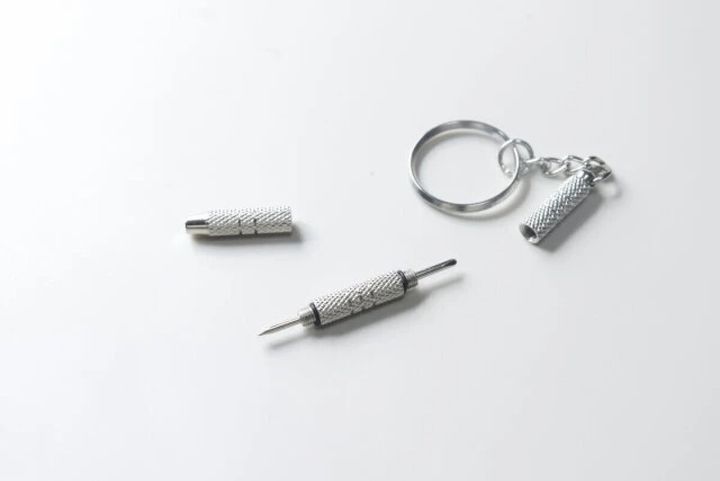 分解された銀色のメガネ専用ドライバーの部品が並べられている