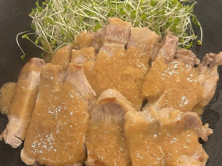 無印良品の粕漬け焼きの素で味付けした豚肉。黒い皿に盛り付け、ブロッコリースプラウトを添えた一品。