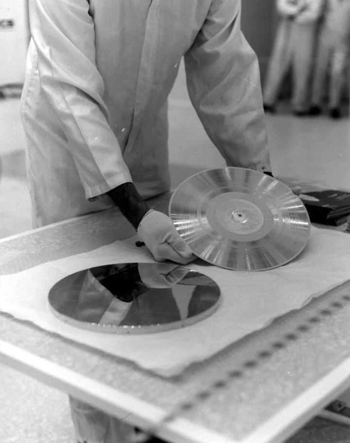 1977年、ボイジャー1号に取り付ける前の金色のレコードを準備しているところです。このレコードがどこかの星の近くにたどり着く日は、まだはるか先です。