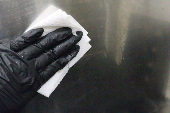 洗剤を含ませたキッチンペーパーでキッチンの壁を拭いている状態