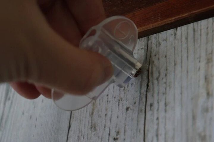 壁の木部に取り付けられたおれくぎにカバーをセットして手で回して外している様子