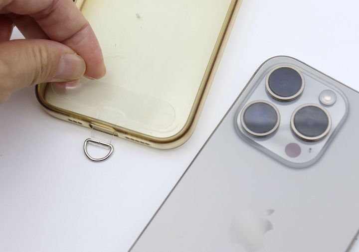 スマートフォンのクリアケースの充電口に透明なアタッチメントを挟み込んでいる手元