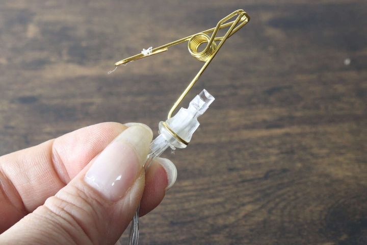 ゴールドのクリップとLEDライトの接続部分を手に持って見せている様子