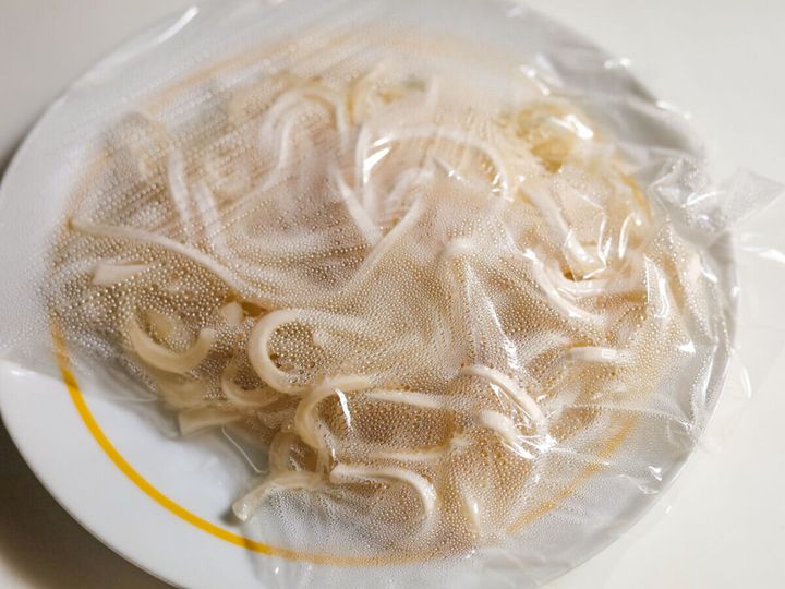 耐熱皿にラップをかけて冷凍うどんを加熱している様子