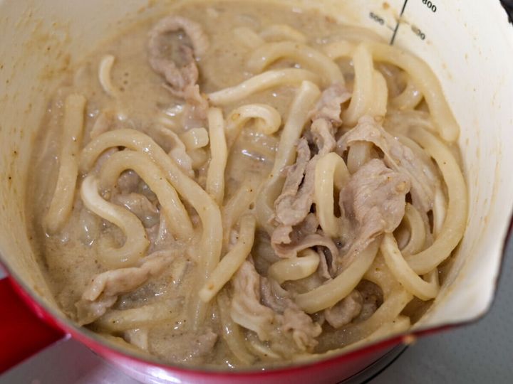 小鍋の中でうどんと豚肉がスープに絡まっている様子