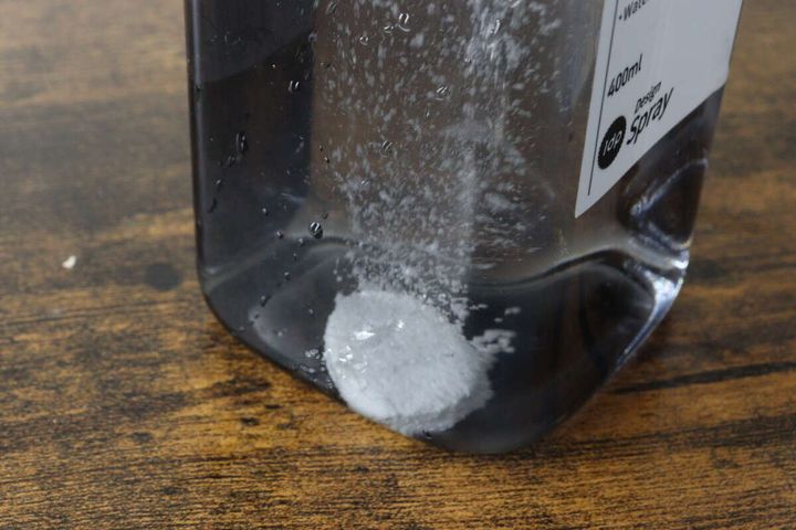 スプレーボトルに入れた水の中で白い錠剤が発泡しながら溶けている状態