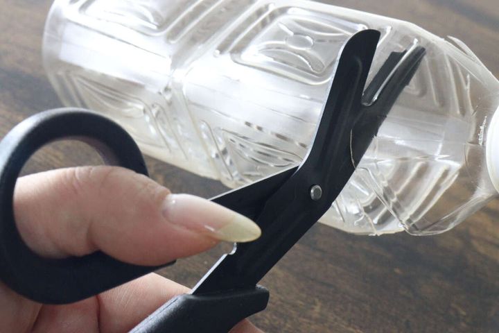 固いプラスチック製のペットボトルを黒いハサミで難なくカットしている場面