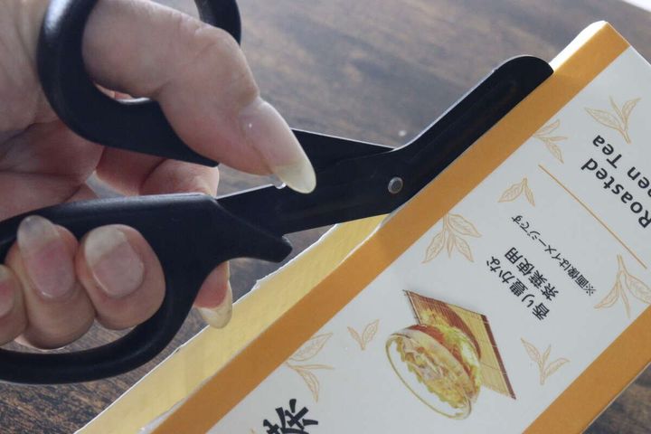 ギザ刃を備えたキッチンハサミで紙パックの側面をスムーズに切っている状態