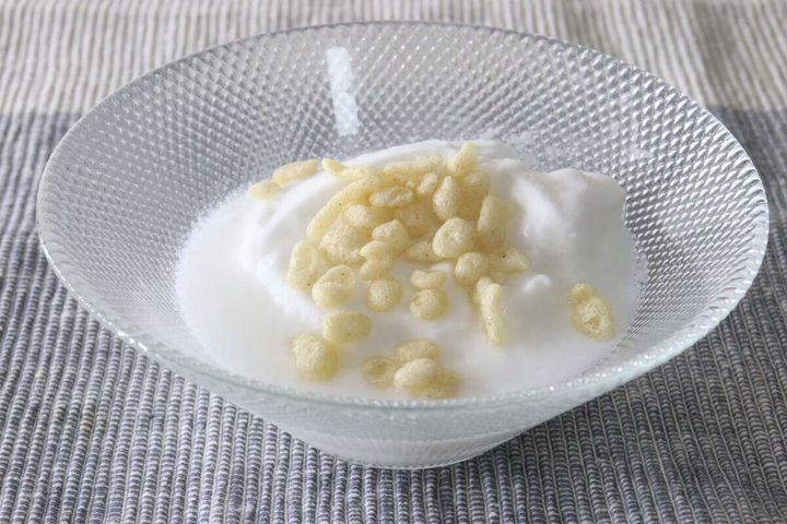 ガラスの器に入った白いヨーグルトの上に雑穀のあげ玉がトッピングされている様子