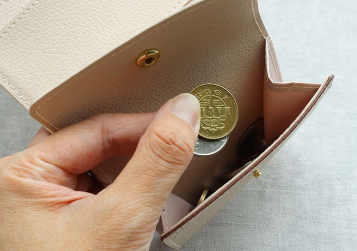 ミニ財布の小銭入れから10円玉を取り出そうとしている手のアップ