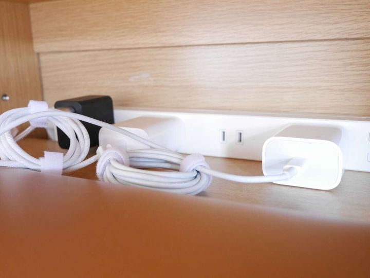 テレビ台の裏で白い電源タップにまとめた白いコードをマジックテープで留めている様子