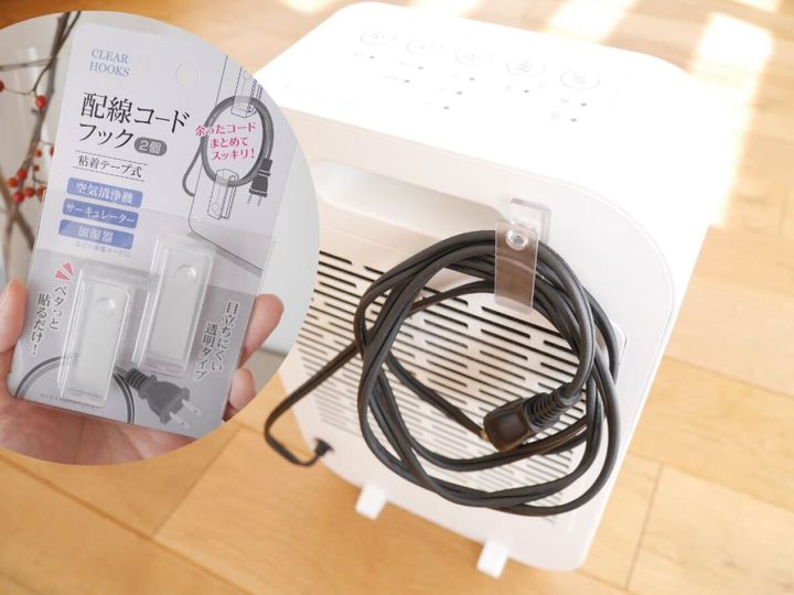 白い空気清浄機の背面にクリアフックを貼り付け黒い電源コードを巻き付けている様子