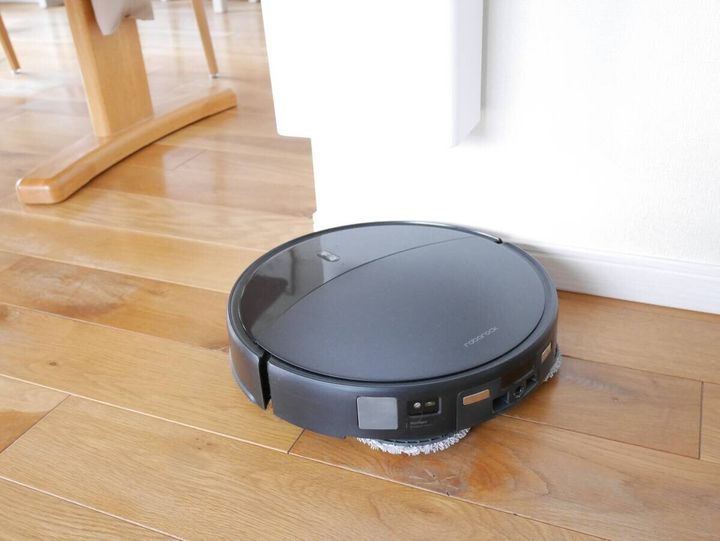 壁掛けゴミ箱の下を黒いロボット掃除機がスムーズに通過している様子