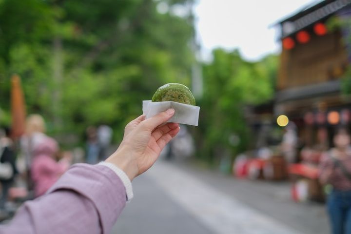 東京のレトロな観光地（深大寺近くの公道）で食べ歩きをする女性が持つ饅頭のクローズアップ 