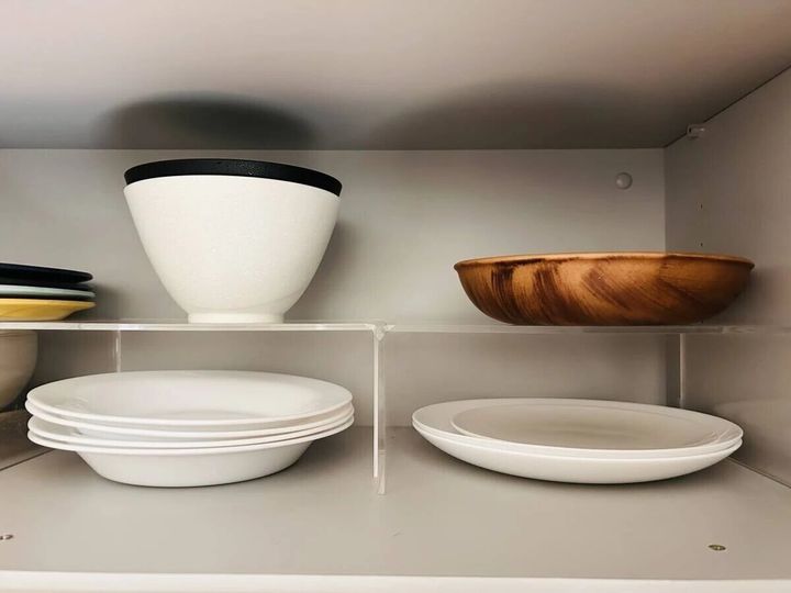 キッチンの食器棚の中でアクリル仕切棚を使いお皿を上下に分けてすっきりと収納している様子