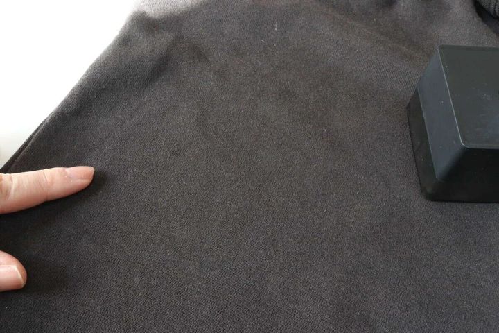 電動毛玉取りを使った後の黒い衣類を指さして確認している様子