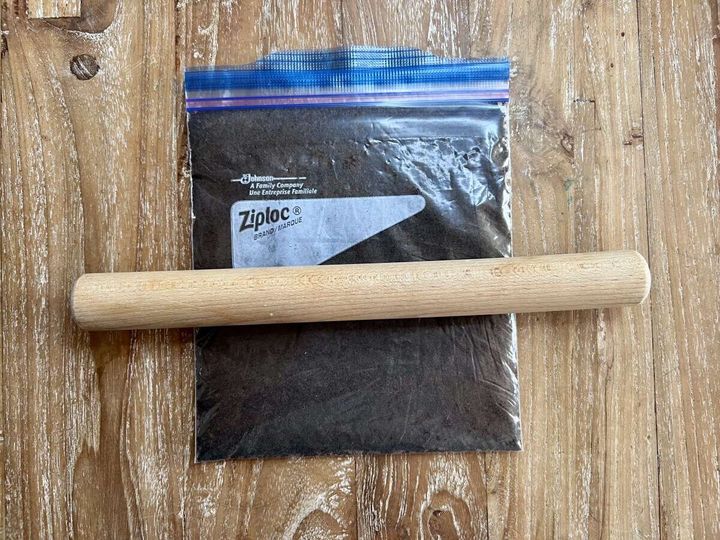 チャック付き保存袋に入ったブラッククッキーの上に木製のめん棒が置かれている