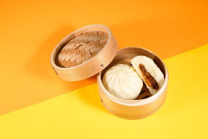 木製の蒸籠に入った丸い中華まんと中身の具材が見えるように半分に割られたとろたま牛すきまん